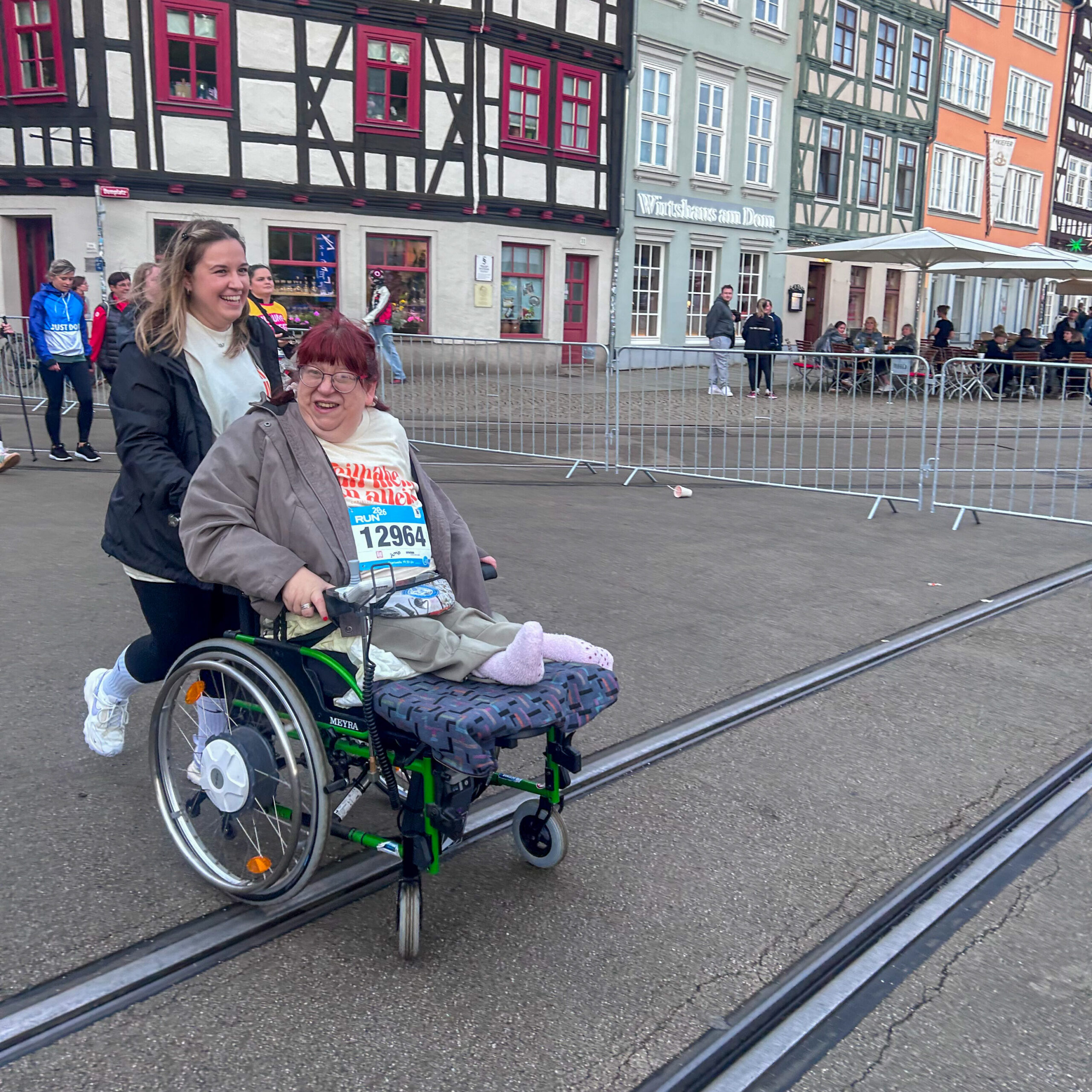 Eine Frau im Rollstuhl wird beim RUN von einer joggenden Mitarbeiterin des Christophoruswerks geschoben.