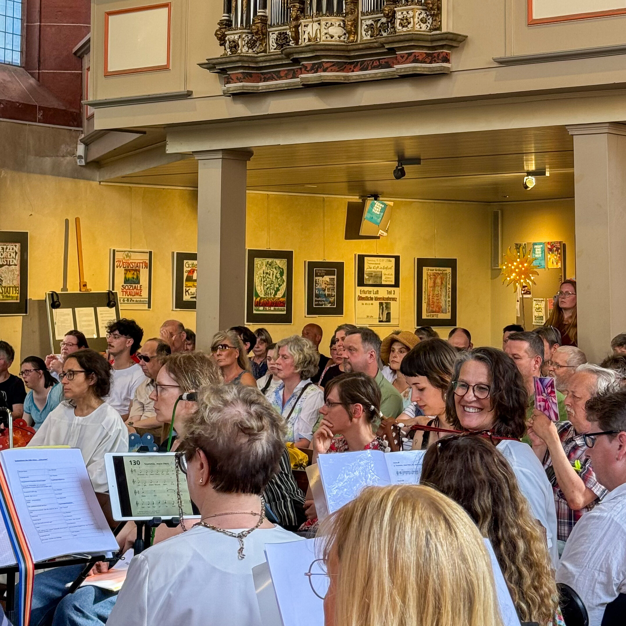 Die Regenbogen Rhythmiks des Christophoruswerk Erfurt musizieren zusammen beim monatlichen Gottesdienst in der Michaeliskirche Erfurt. Im Hintergrund lauschen die Besucher.